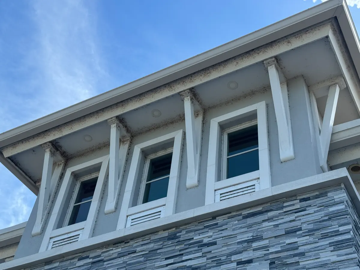 A close view of the eaves, window trim and stone accents on a house wall.