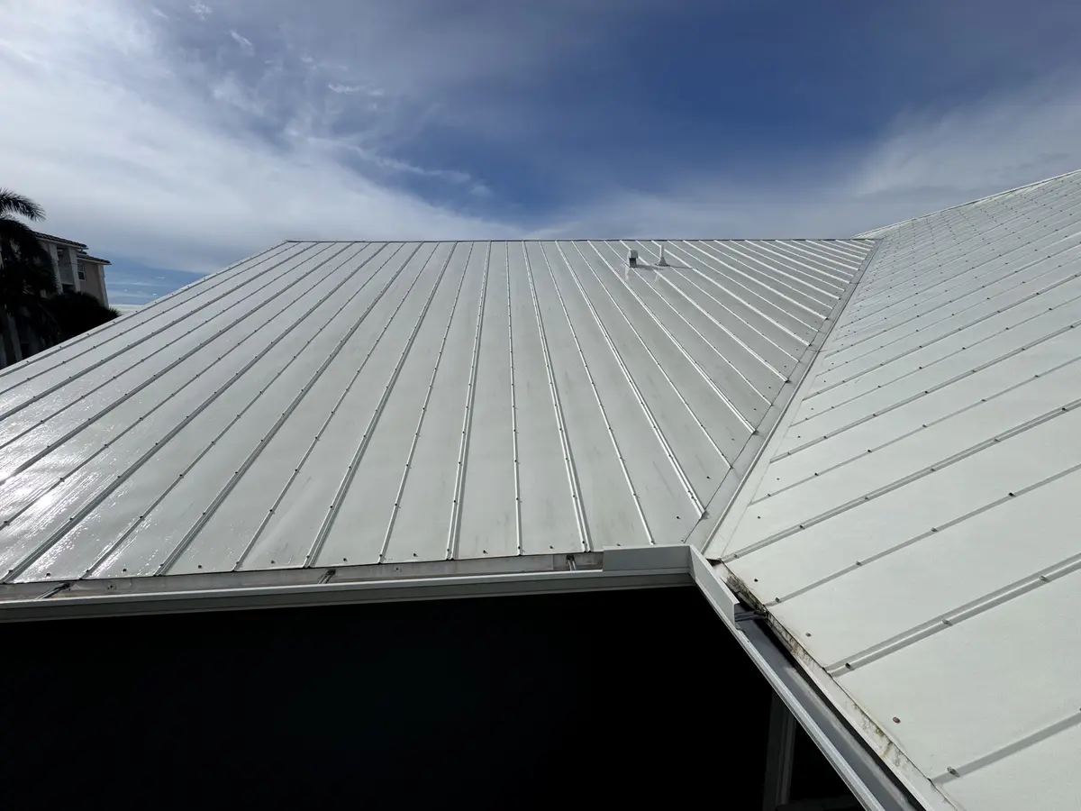A cleaned section of metal roof under a clear sky.